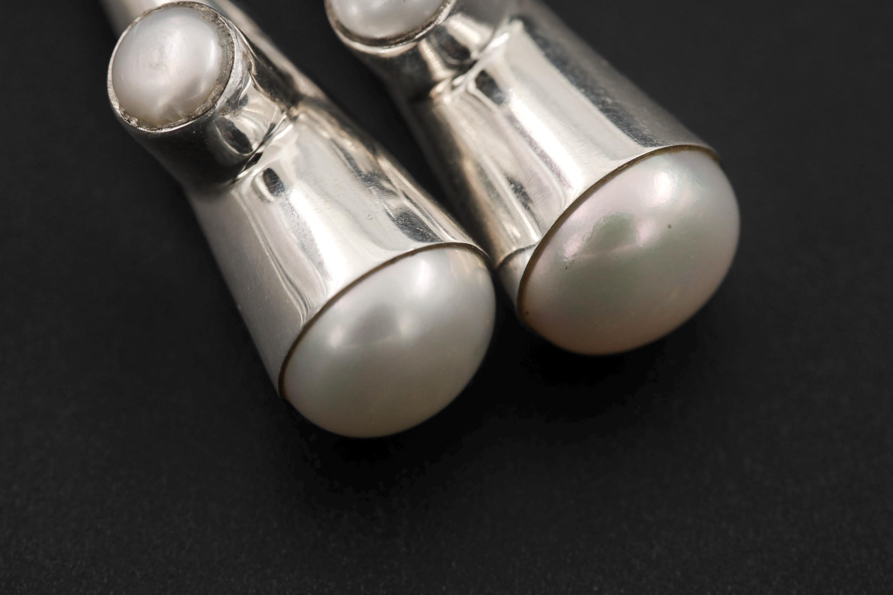 Close view of Pearl Cone Drop Earrings showing polished silver cones and luminous white Pearl bases.