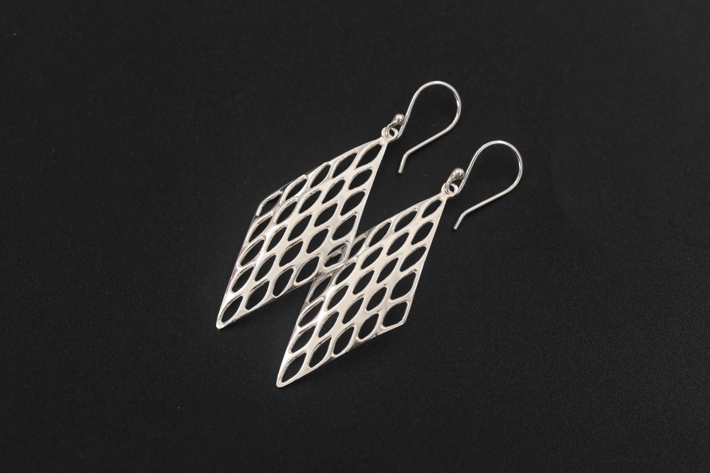 Sterling silver lattice earrings displayed on dark stone with open diamond-shaped geometric design.