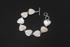 Mother of Pearl sterling silver bracelet displayed on dark background with repeating heart-shaped shell links.