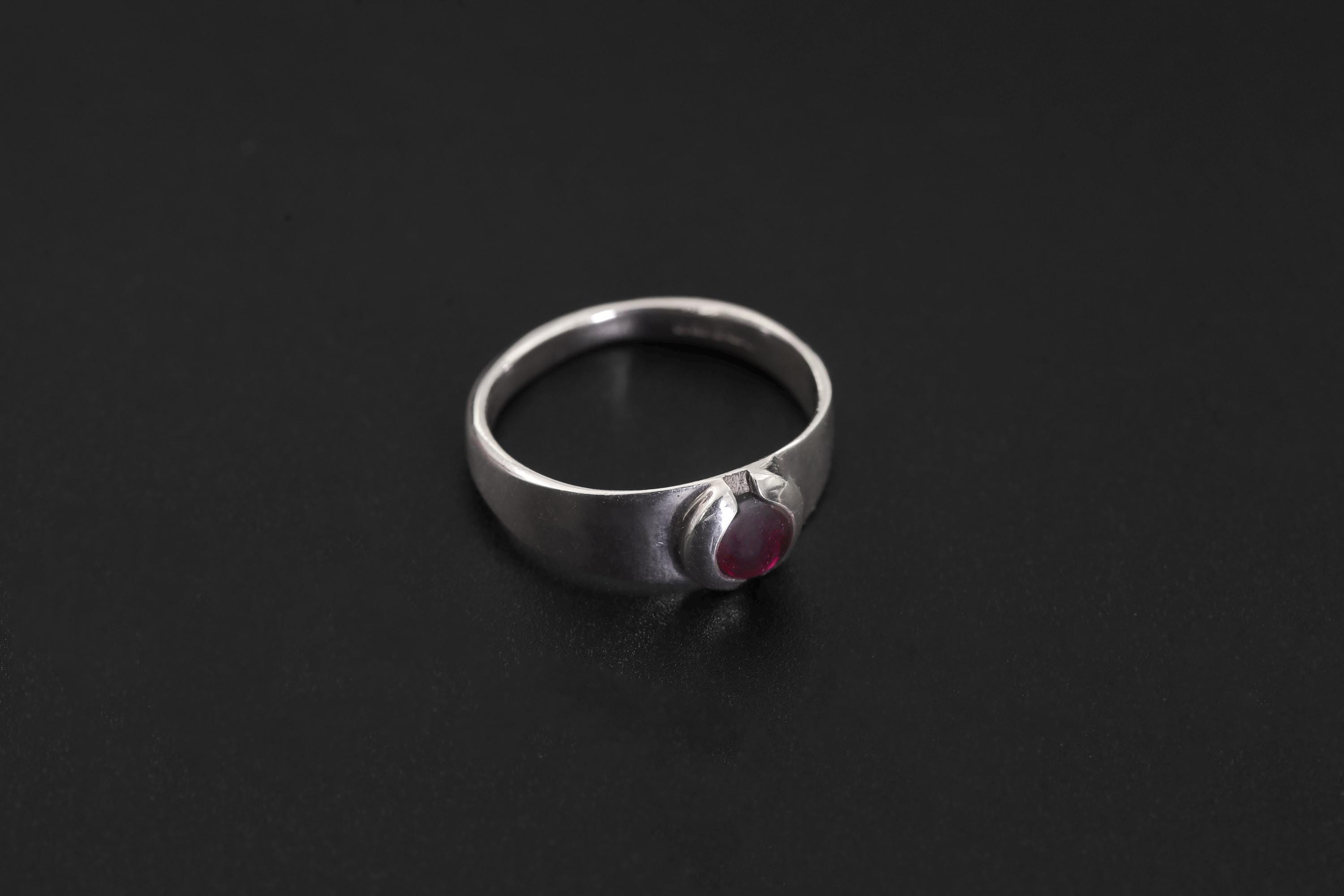 Side view of polished Garnet ring showing bezel-style setting and rounded silver band.