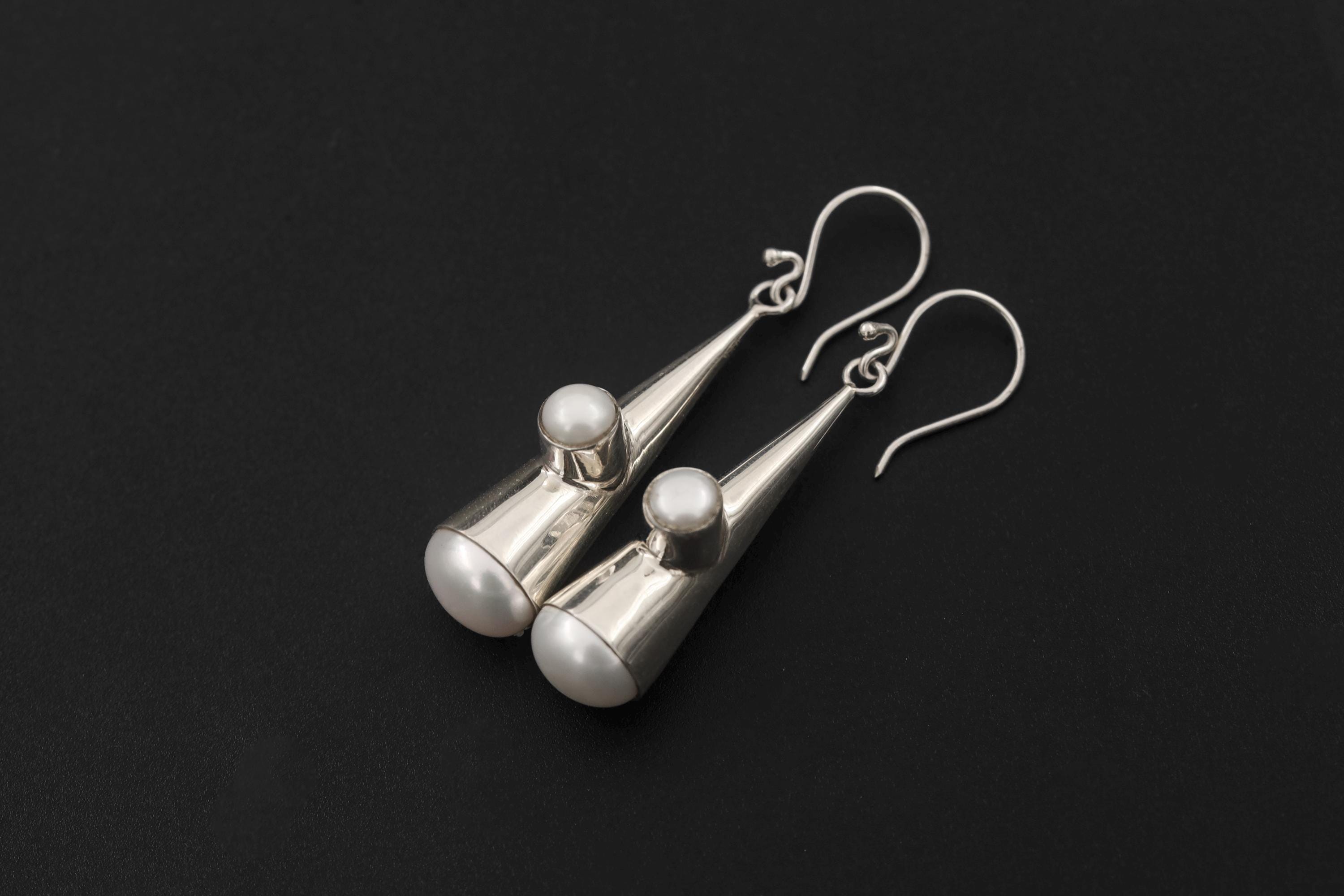 Pearl earrings shown in hand with mirror-polished sterling silver cone shape and side Pearl accents.