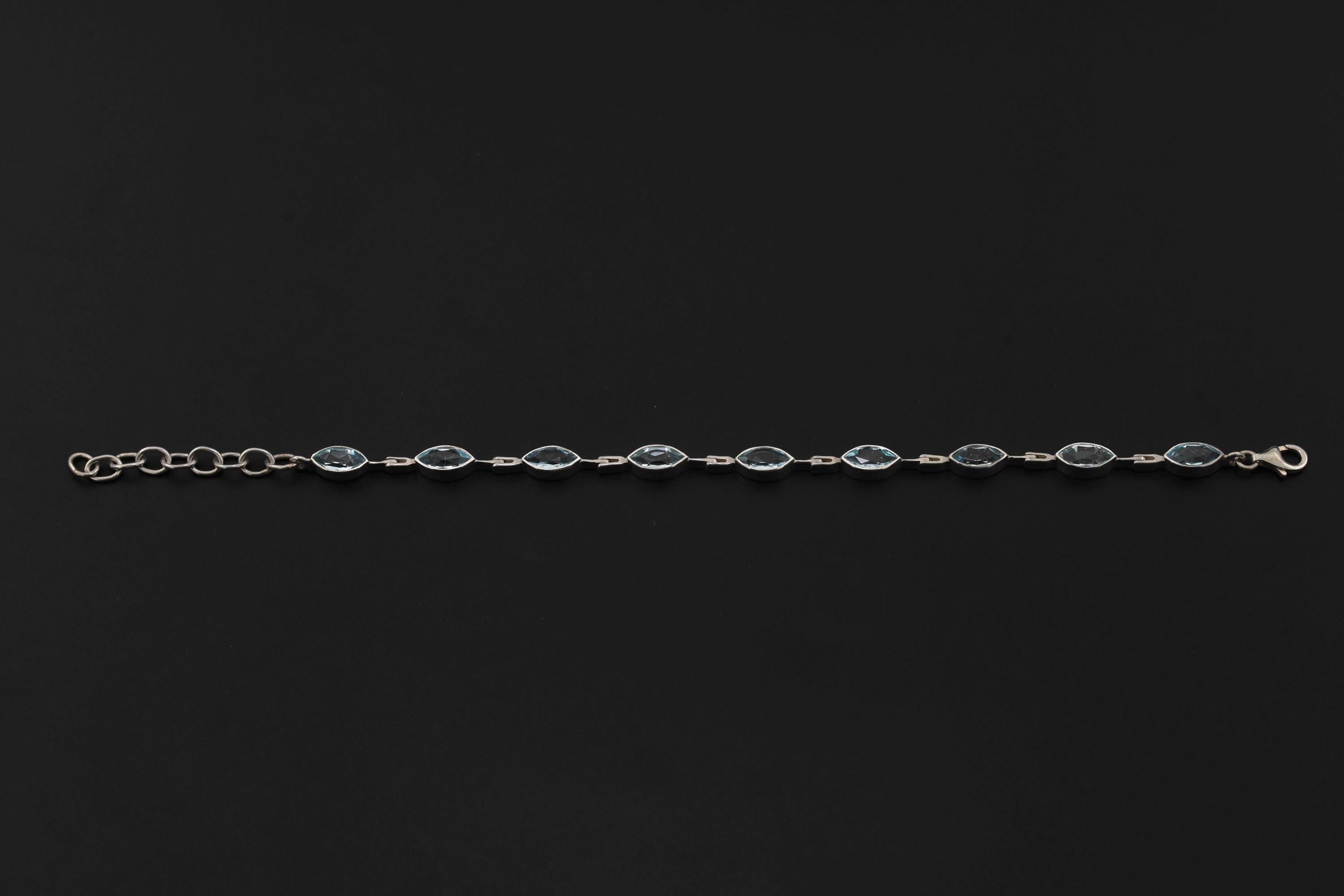 Blue Topaz sterling silver bracelet displayed on dark background with flowing marquise gemstone sequence.