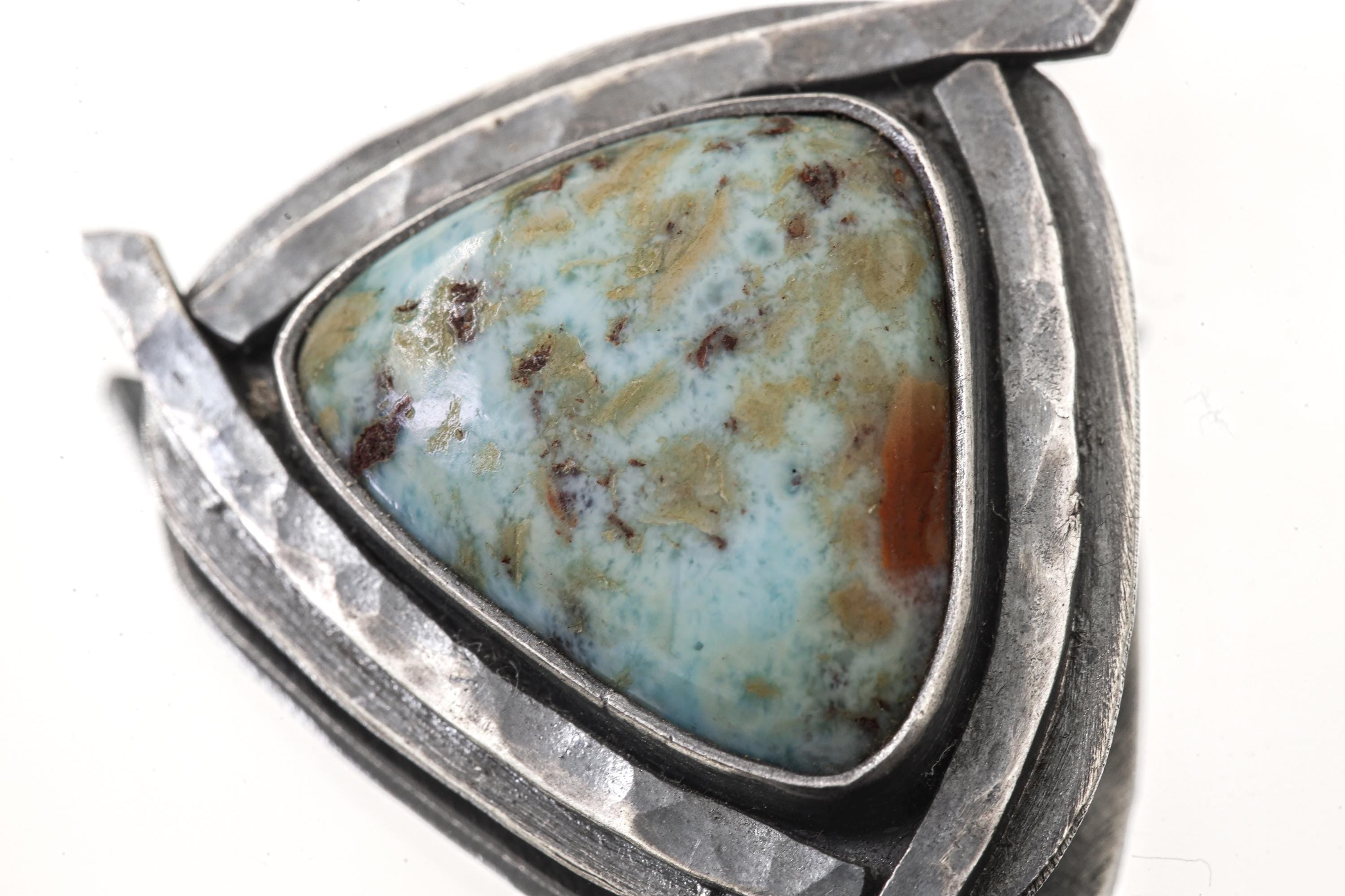 Close-up of Larimar triangle pendant showing blue white stone pattern and oxidized silver sun details.