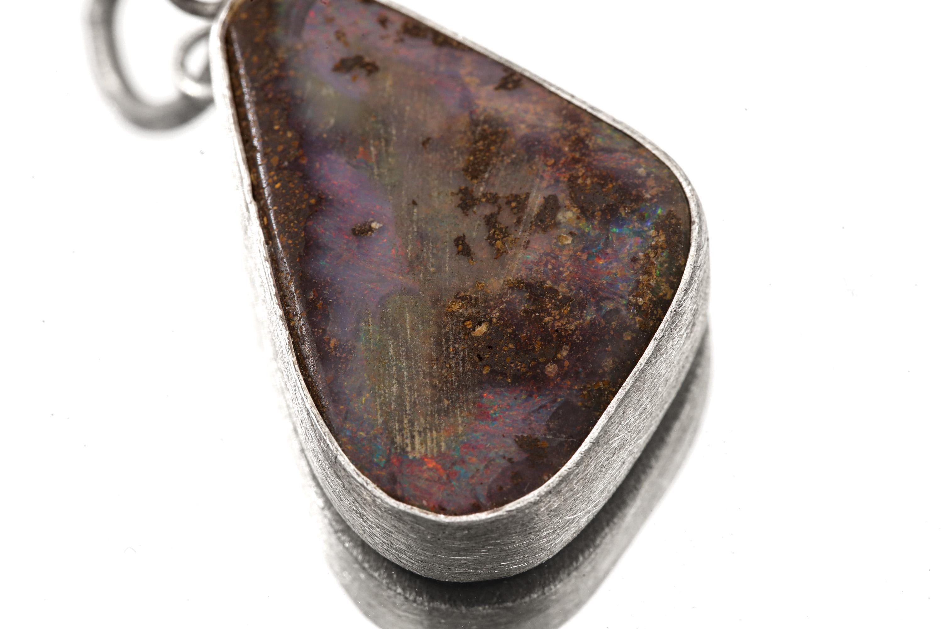 Close-up of solid Lightning Ridge Boulder Opal showing earthy matrix, violet tones, and textured sterling silver bezel.