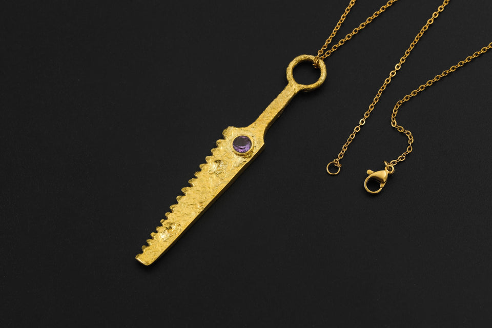 Amethyst cutter spoon pendant displayed with gold-plated brass body and chain.