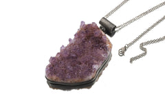 Raw Amethyst cluster pendant shown with silver chain on white background and oxidized sterling silver setting.