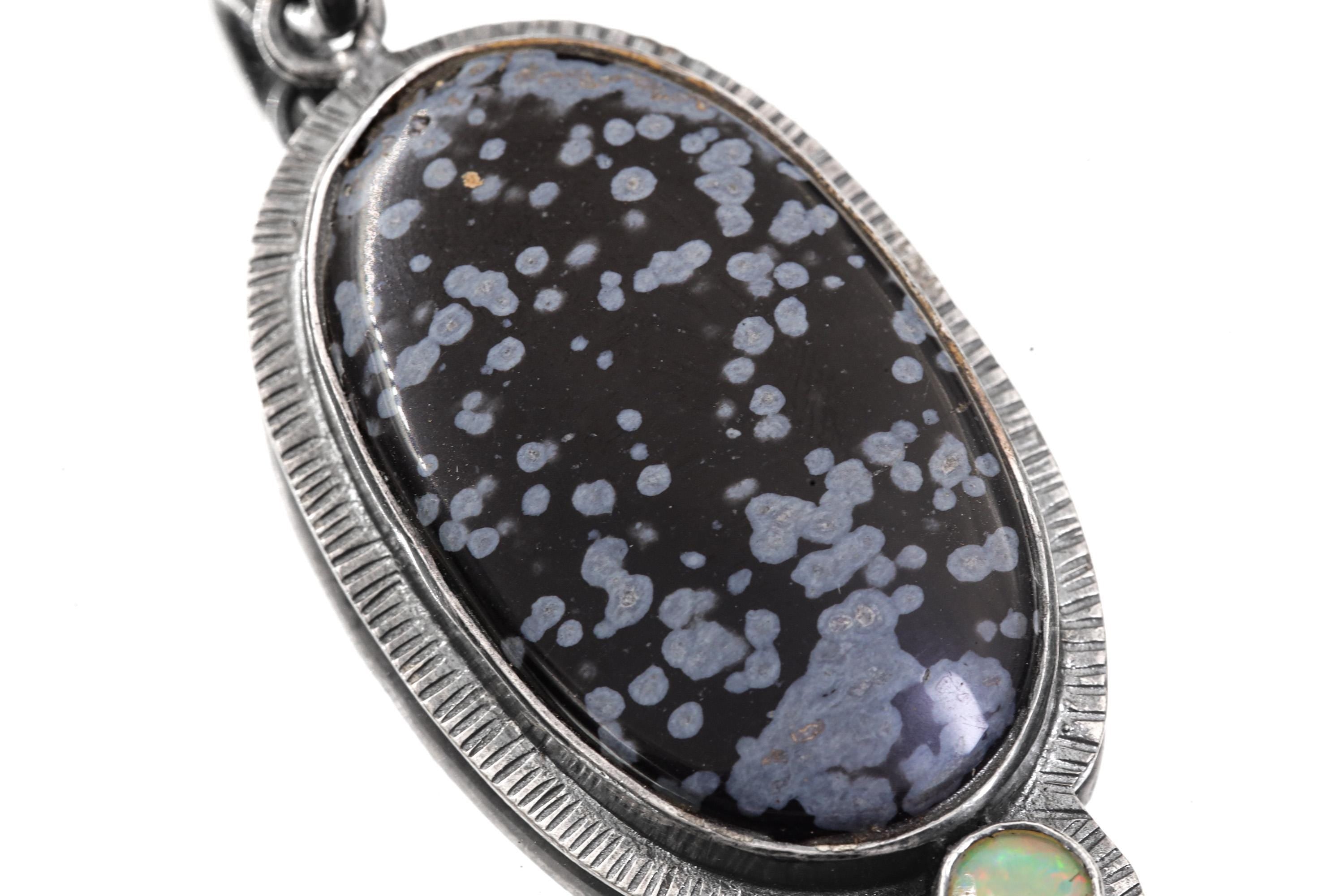 Close-up of Dalmatian Jasper Ethiopian Opal pendant showing opal flash and radiating silver line detail.
