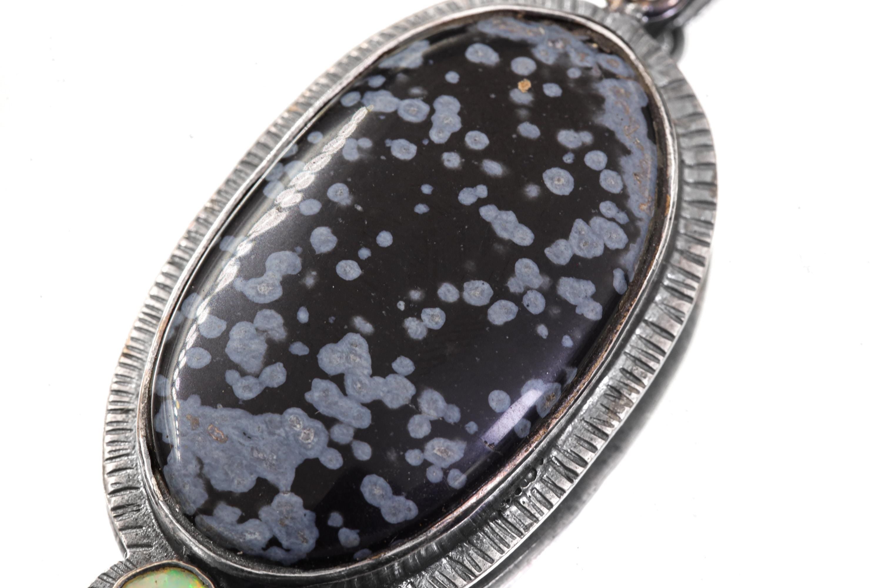 Close-up of Dalmatian Jasper pendant showing spotted black and grey patterning in textured sterling silver frame.
