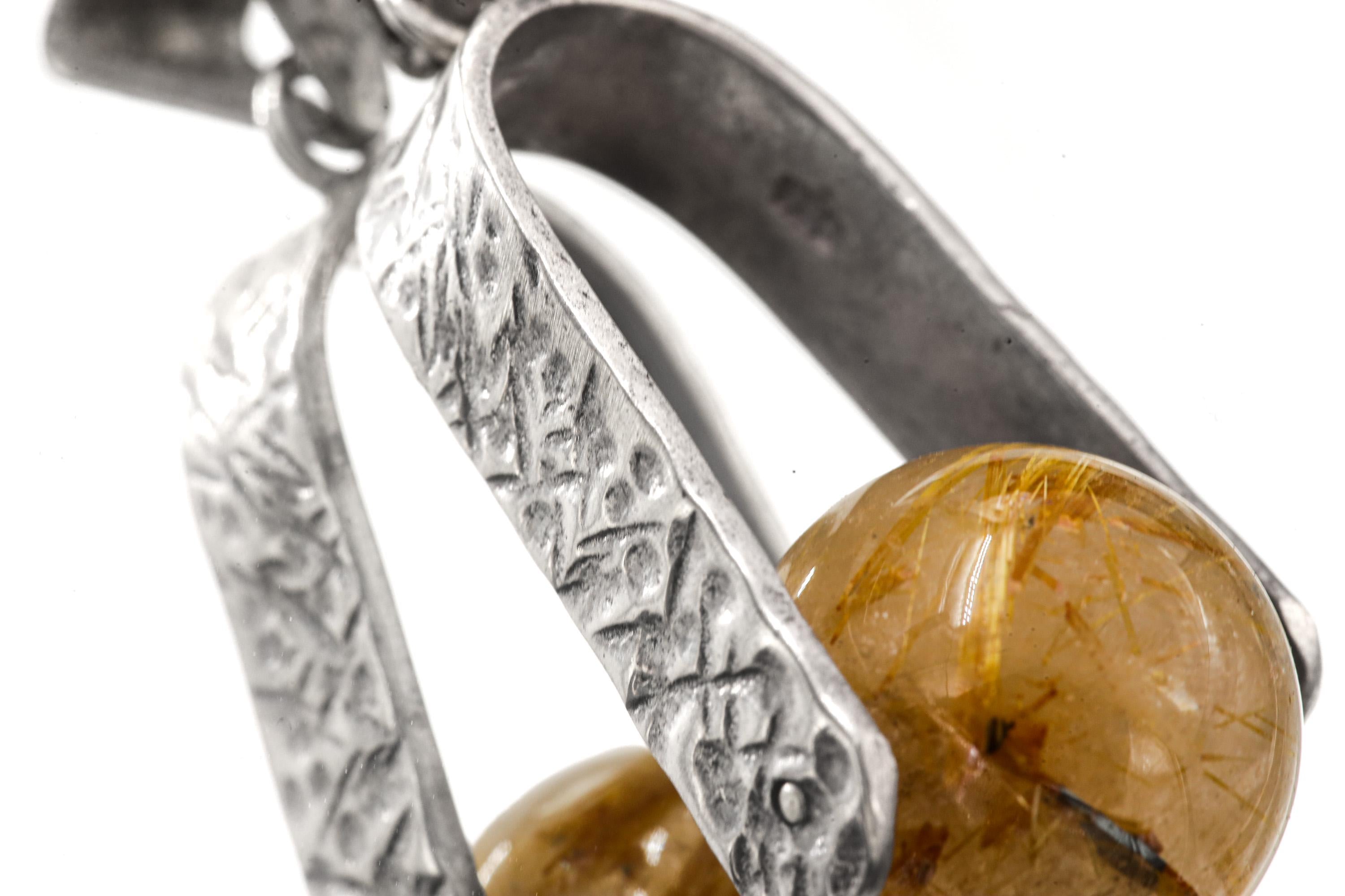 Hammer-textured sterling silver arch holding a rotating Golden Rutilated Quartz crystal sphere.