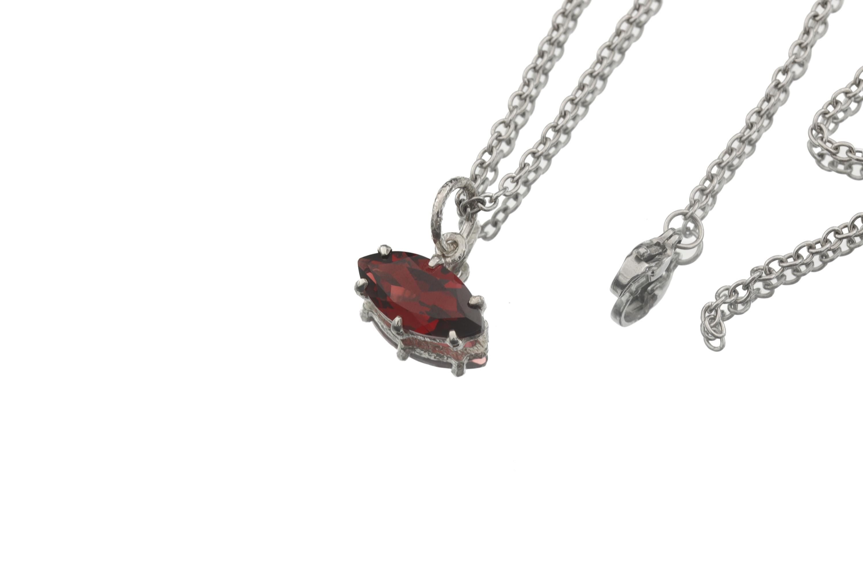 Garnet marquise pendant displayed on dark slate with sterling silver chain and red gemstone glow.