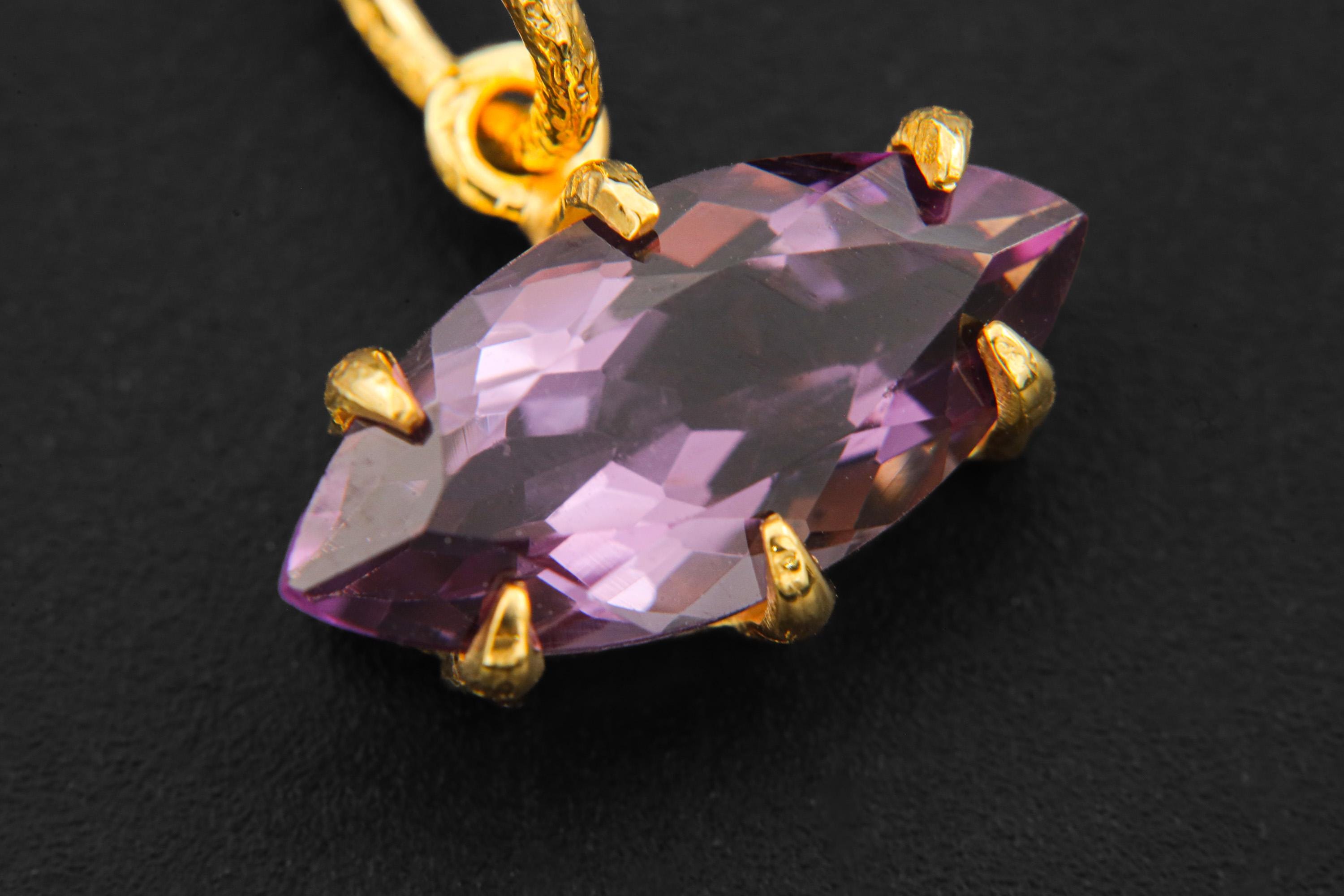 Close view of faceted Amethyst pendant showing violet stone in gold-plated claw setting.