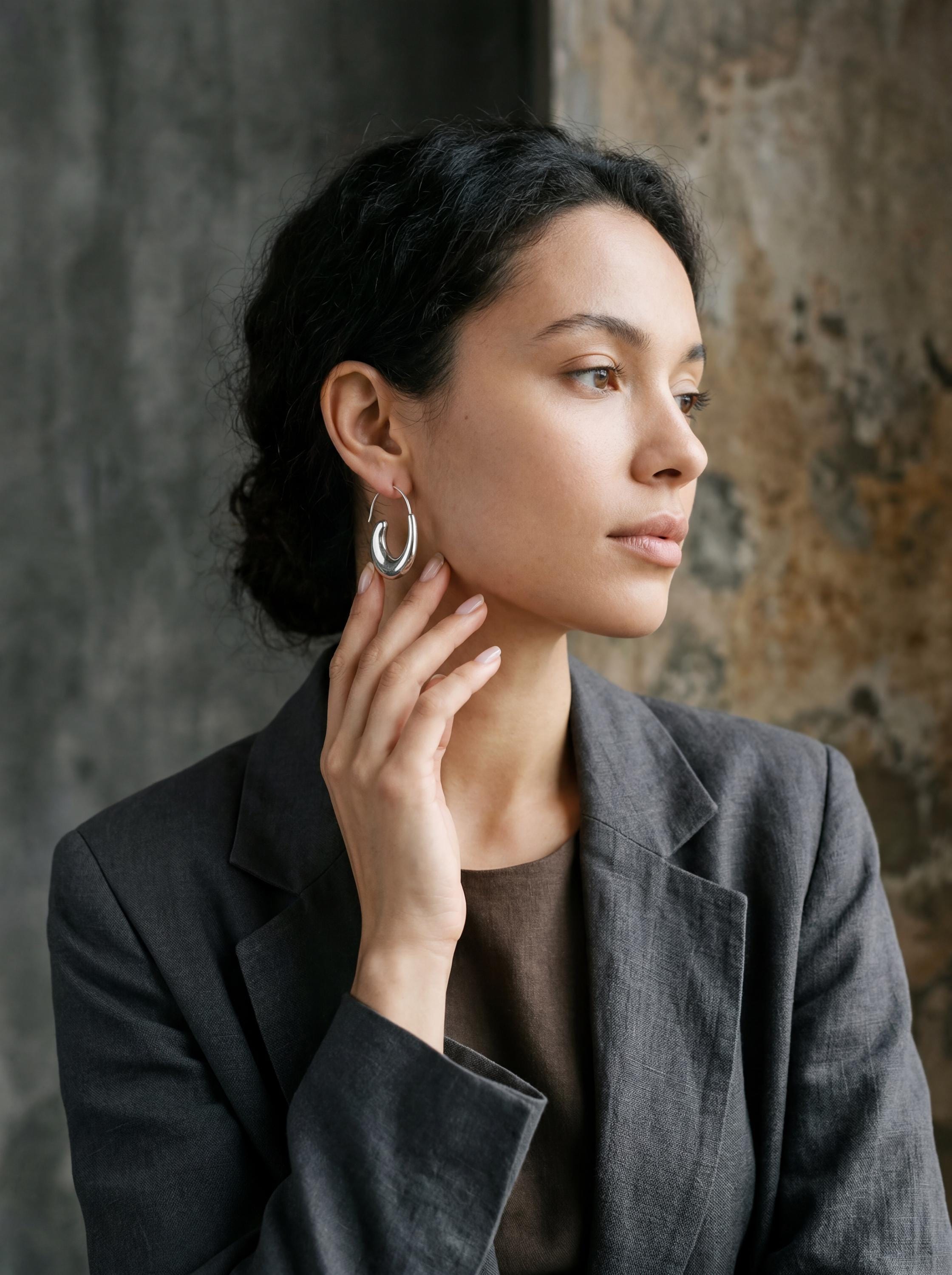 Sterling silver crescent hoop earrings shown on model with clean modern ocean-inspired styling.