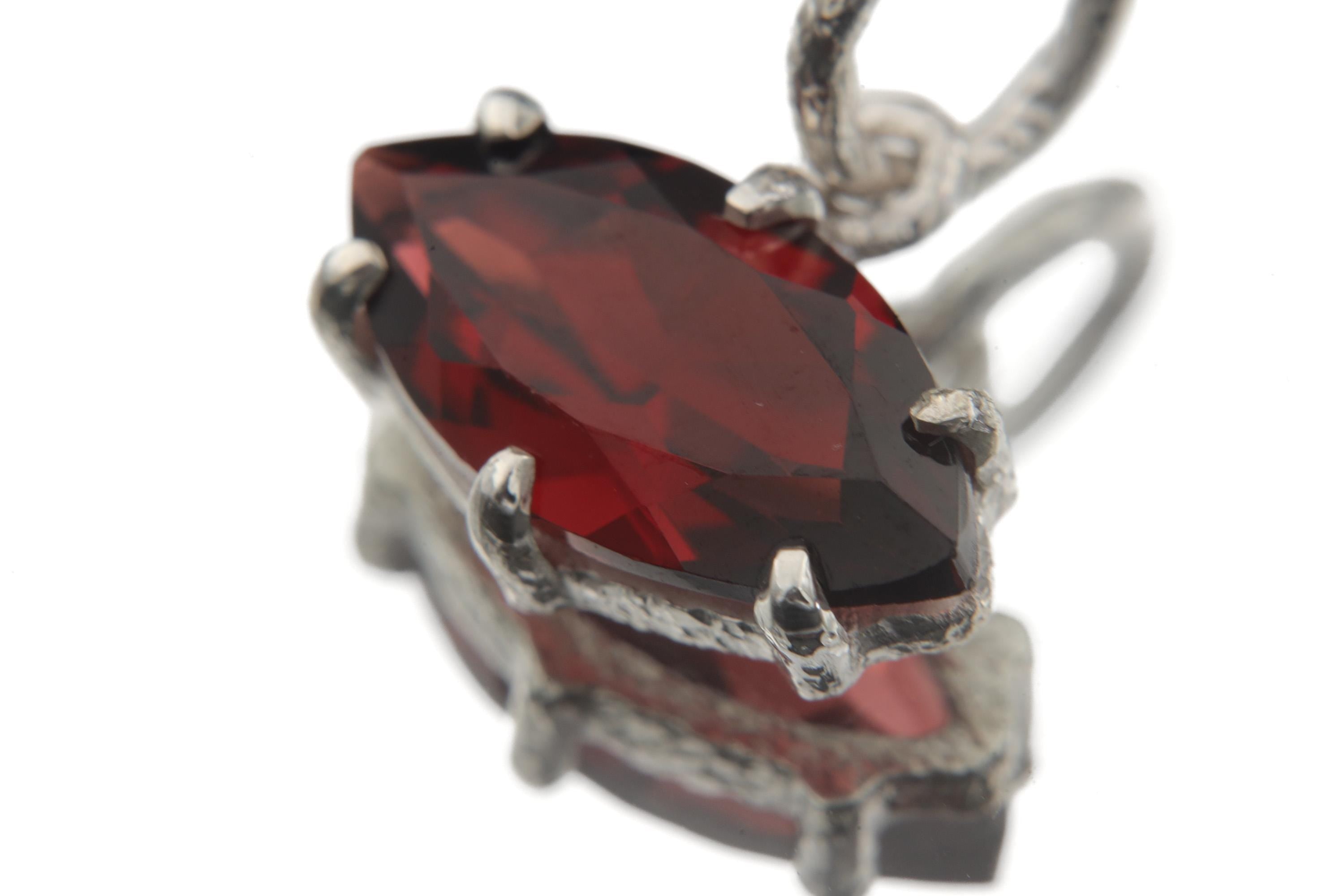 Close view of faceted Garnet pendant in sterling silver claw setting with deep crimson colour.