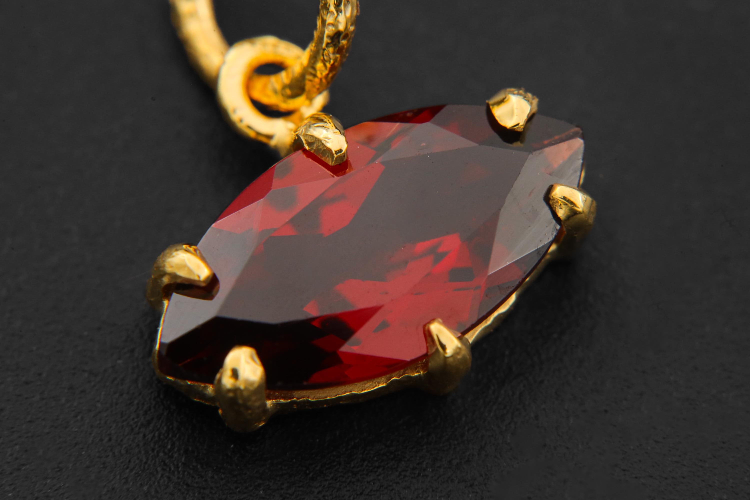 Close view of Garnet marquise pendant showing deep wine-red facets in gold-plated silver claws.