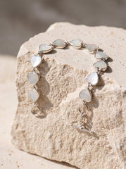 Mother of Pearl heart bracelet shown on textured stone with polished sterling silver settings and toggle clasp.