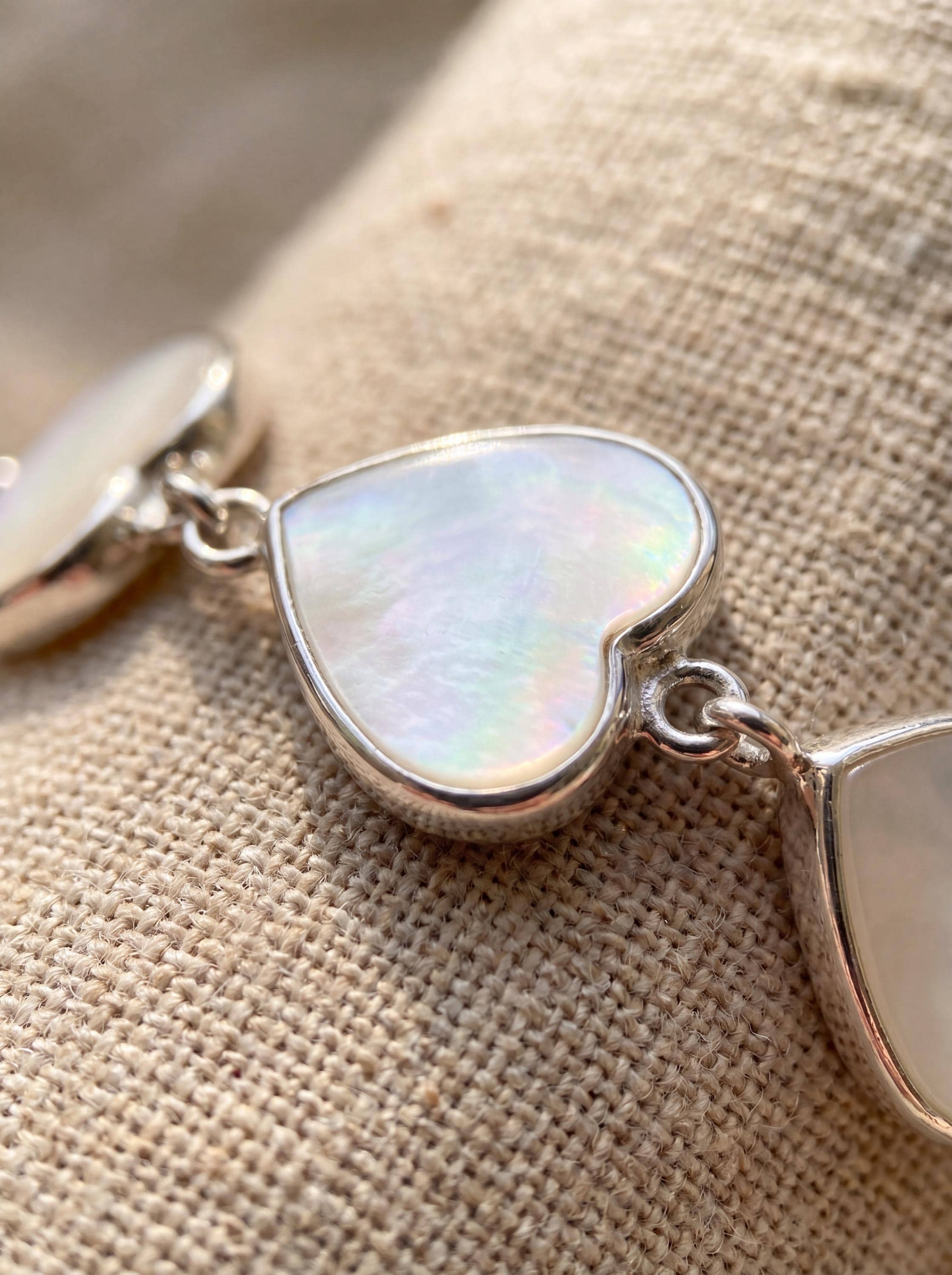 Close view of Mother of Pearl heart bracelet showing creamy nacre shimmer in polished silver setting.