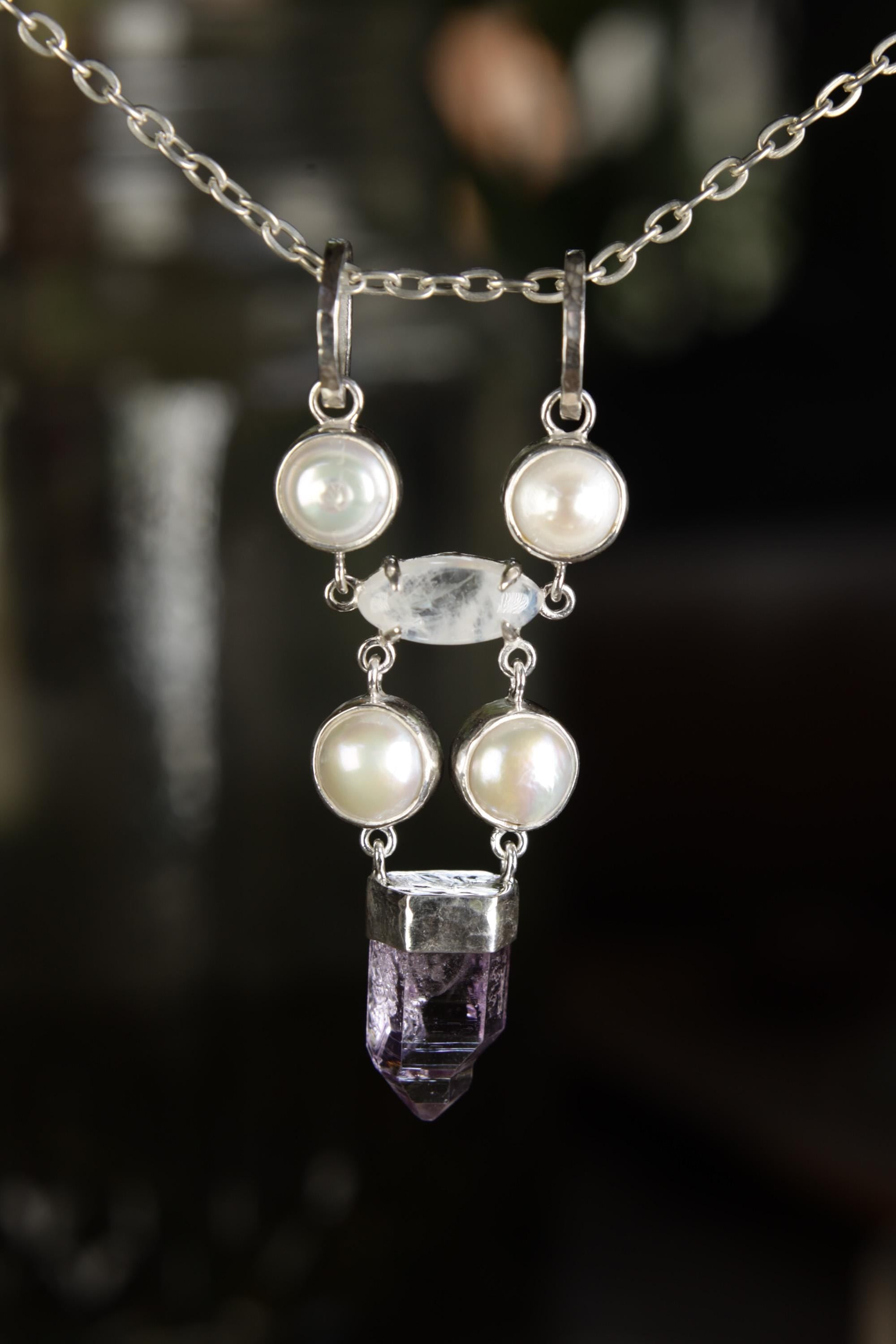 South Sea Pearl Moonstone Amethyst pendant shown hanging outdoors, with symmetrical Pearl layout and violet crystal point.
